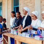 Voluntários distribuem cadernos a crianças durante uma ação comunitária ao ar livre.