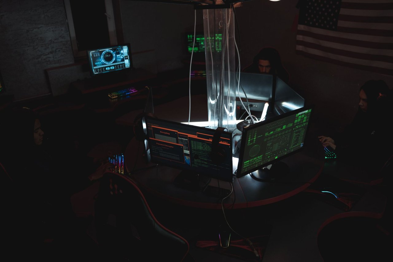 Equipe de profissionais acompanha dados e sistemas em computadores de uma sala de operações de cibersegurança.
