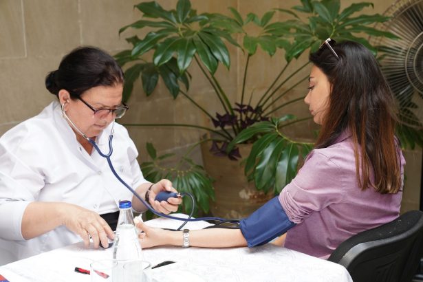 Profissional de saúde mede a pressão arterial de uma mulher em um atendimento ao ar livre.