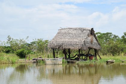 Casa ribeirinha junto a um rio, cercada pela vegetação da Amazônia